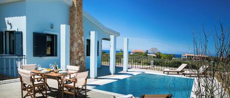 A poolside area with a table set for dining, lounge chairs, and a stone tower structure.