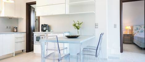 Uma cozinha moderna com armários brancos, uma ilha central com cadeiras e um vaso com flores.