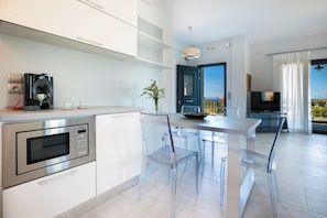 Eine moderne Küche mit eingebauter Mikrowelle, einer Kaffeemaschine und einem Essbereich mit transparenten Stühlen und einem Tisch.