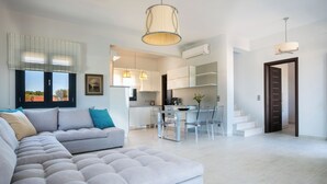 Een moderne woonkamer met een hoekbank, een eethoek met een tafel en stoelen, en een keuken op de achtergrond.