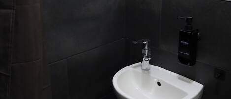 Un baño con un lavamanos blanco, un espejo y un toallero negro.