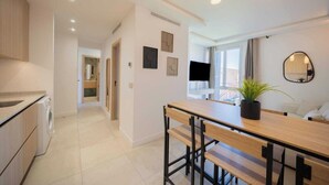 A modern kitchen with a washing machine, a dining area with a wooden table and chairs, a potted plant, and a large window with a view. - Charming apartment - 2BDR/6P - Saint Tropez/Port (Saint-Tropez)