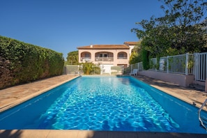 A swimming pool with a clear blue water surface, surrounded by a white fence, and a building with a tiled roof in the background. - 6P apartment in a Citadelle /POOL - Saint-Tropez (Saint-Tropez)