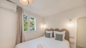 Una camera da letto con un letto, una finestra con tende, un comodino e uno specchio.