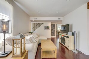 Ein modernes Wohnzimmer mit einer Couch, einem Holztisch, einem Fernseher und einer Küchenzeile mit Schränken und einem Herd.