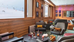 A cozy lounge area with wooden walls, large windows, and a ski slope view. - Modern Twin Room with Ski Facilities (La Plagne-Tarentaise)