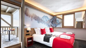 A hotel room with a bed, a nightstand, a table with a lamp, a window with a view of mountains, and a balcony. - Modern Twin Room with Ski Facilities (La Plagne-Tarentaise)