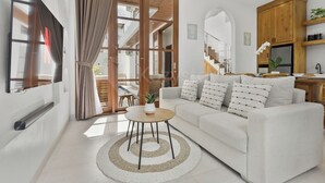A modern living room with a sofa, coffee table, and curtains. - Calyra Villa by Kozystay - Ungasan (Ungasan)