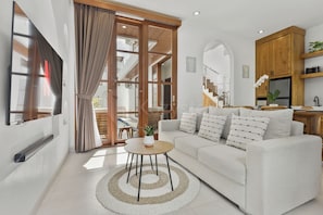 A modern living room with a sofa, coffee table, and curtains. - Calyra Villa by Kozystay - Ungasan (Ungasan)