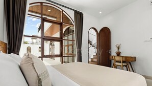 A bedroom with a large bed, a desk, and a view of the outside. - Calyra Villa by Kozystay - Ungasan (Ungasan)