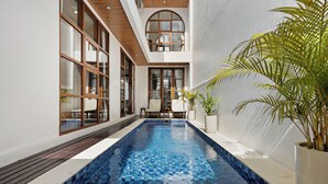 A swimming pool with a tiled floor, wooden deck, and potted plants. - Calyra Villa by Kozystay - Ungasan (Ungasan)