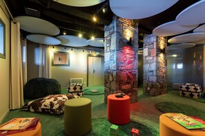 Ein gemütlicher Lounge-Bereich mit Steinwand, bequemen Sitzmöglichkeiten und einem kleinen Tisch mit einem Buch.