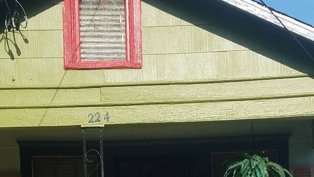 A house with a green exterior, a black metal gate, and two flower pots on the front steps. - Adorable Tiny House Near Mercedes Benz Stadium (Atlanta)