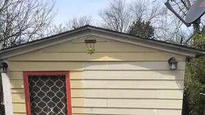 A small shed with a 'WELCOME' sign, a door with a decorative screen, and two red chairs with white stripes on a patterned rug. - Adorable Tiny House Near Mercedes Benz Stadium (Atlanta)