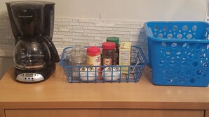 A kitchen counter with a coffee maker, a basket of items, and a blue basket. - Adorable Tiny House Near Mercedes Benz Stadium (Atlanta)