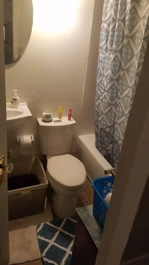 A small bathroom with a toilet, sink, and shower curtain. - Adorable Tiny House Near Mercedes Benz Stadium (Atlanta)