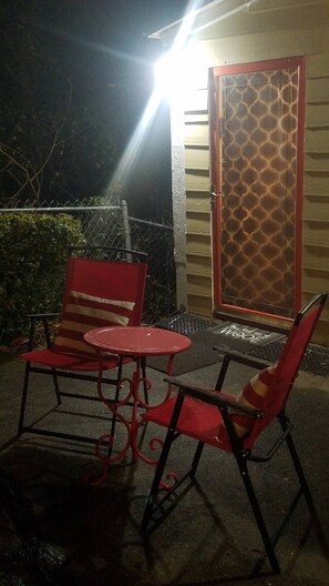 An outdoor seating area with a table and two chairs, a door with a patterned design, and a fence. - Adorable Tiny House Near Mercedes Benz Stadium (Atlanta)