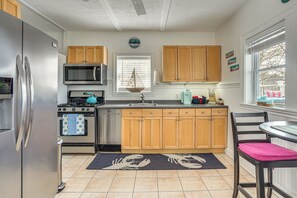 Una cocina con armarios de madera, electrodomésticos de acero inoxidable, un microondas y un lavamanos.