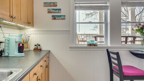 Een keuken met houten kastjes, een aanrecht met een koffiezetapparaat en een raam met uitzicht op het omliggende landschap.