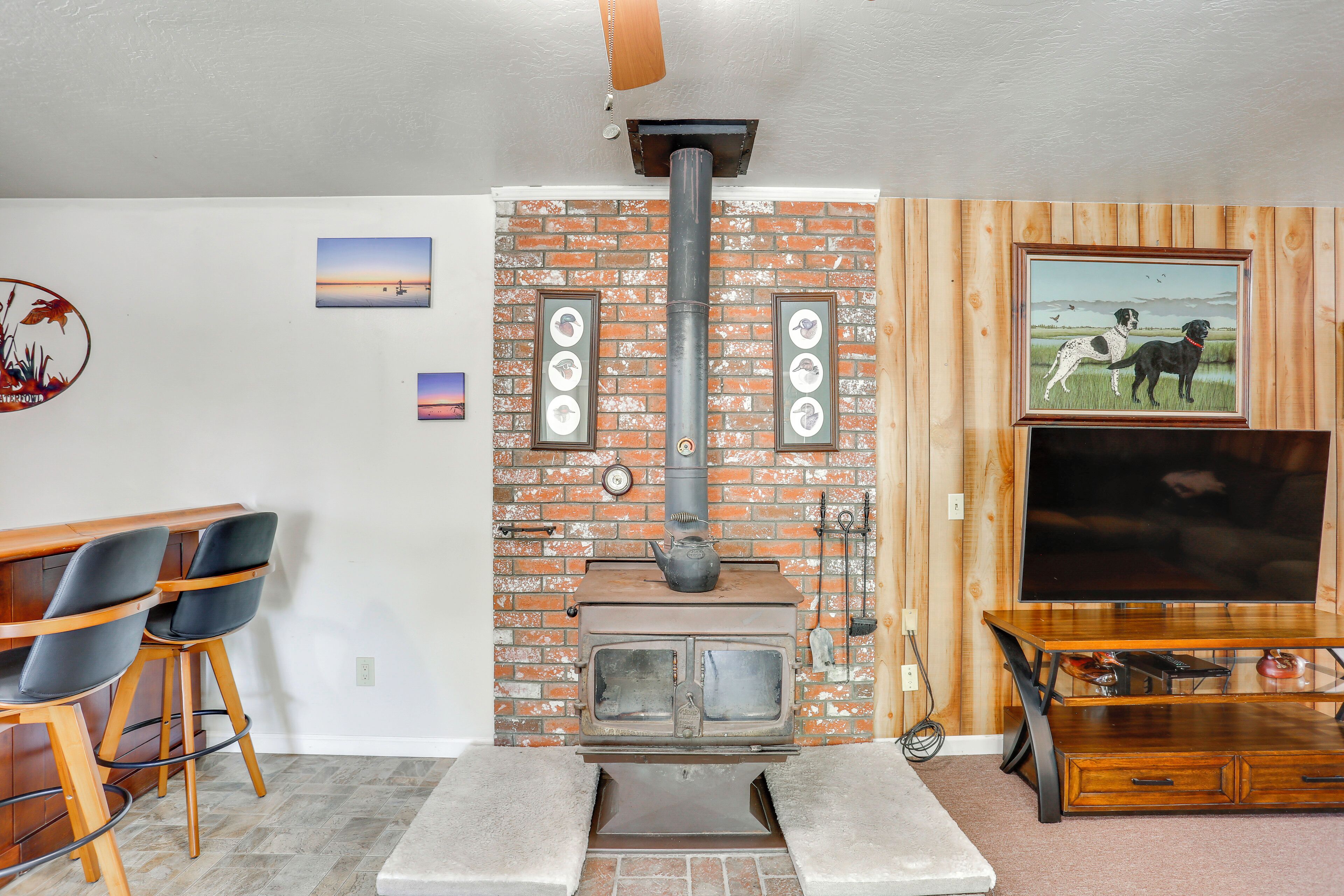 Un salón con chimenea de ladrillo, muebles de madera y televisor.