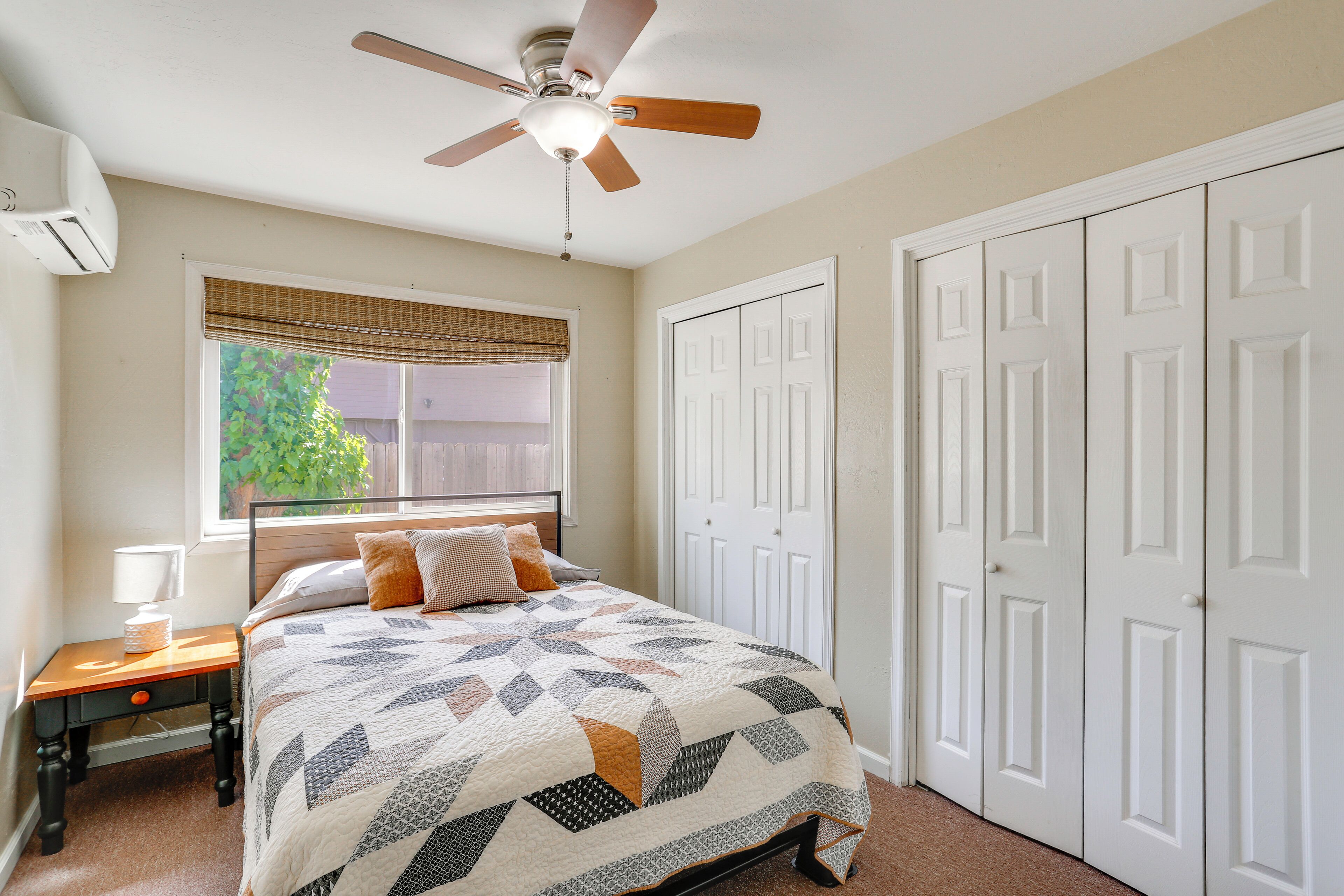 A bedroom with a bed, a nightstand, a ceiling fan, a window with blinds, and a closet.