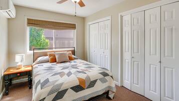 A bedroom with a bed, a nightstand, a ceiling fan, a window with blinds, and a closet.