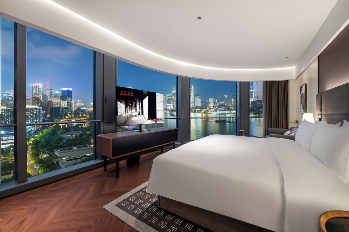 Camera d'albergo moderna con un letto grande, una scrivania e una TV, con vista sulla città.