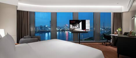 A modern hotel room with a large bed, a desk, and a television.