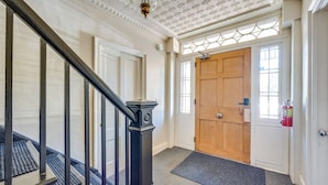 Un escalier avec des balustrades noires, une porte en bois dotée d’un panneau de verre et un extincteur fixé au mur.