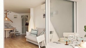 Ein Essbereich mit Tisch für vier Personen, einer Couch und einer Treppe zu einer oberen Ebene.