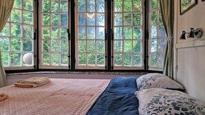 Ein Bett mit einer gesteppten rosa Decke, einem blauen Bettüberwurf und gemusterten Kissen.