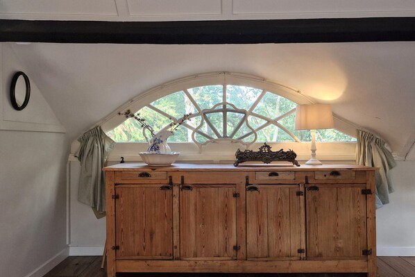 A wooden cabinet with a window above it, a vase, and a lamp on the windowsill. - Historic Romantic Pavilion Retreat for 4 (Ronzon (Rendeux))