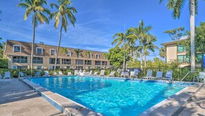 A rectangular swimming pool with clear blue water, surrounded by lounge chairs and palm trees. - Poolside Fun, Ocean Strolls! Naples Beach Getaway (Naples)