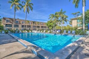 A rectangular swimming pool with clear blue water, surrounded by lounge chairs and palm trees. - Poolside Fun, Ocean Strolls! Naples Beach Getaway (Naples)