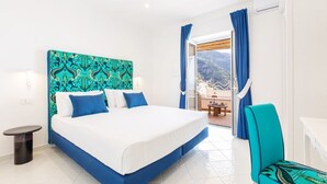 Ein Hotelzimmer mit Bett, Sessel, kleinem Tisch und Blick ins Freie.