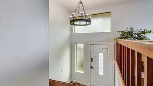 A staircase with a wooden handrail, a white door with a glass panel, and a chandelier. - Lake View! South End Seattle Home Near Lumen Field (Seattle)