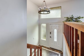 Eine Treppe mit einer Holzhandläufe, eine weiße Tür mit Glasfenster und eine Kristallleuchter.