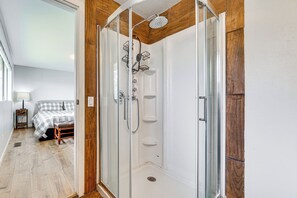 A glass-enclosed shower with a handheld showerhead, a built-in shelf, and a shower caddy. - Lake View! South End Seattle Home Near Lumen Field (Seattle)