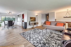 Ein modernes Wohnzimmer mit Sofa, Couchtisch und Essbereich.