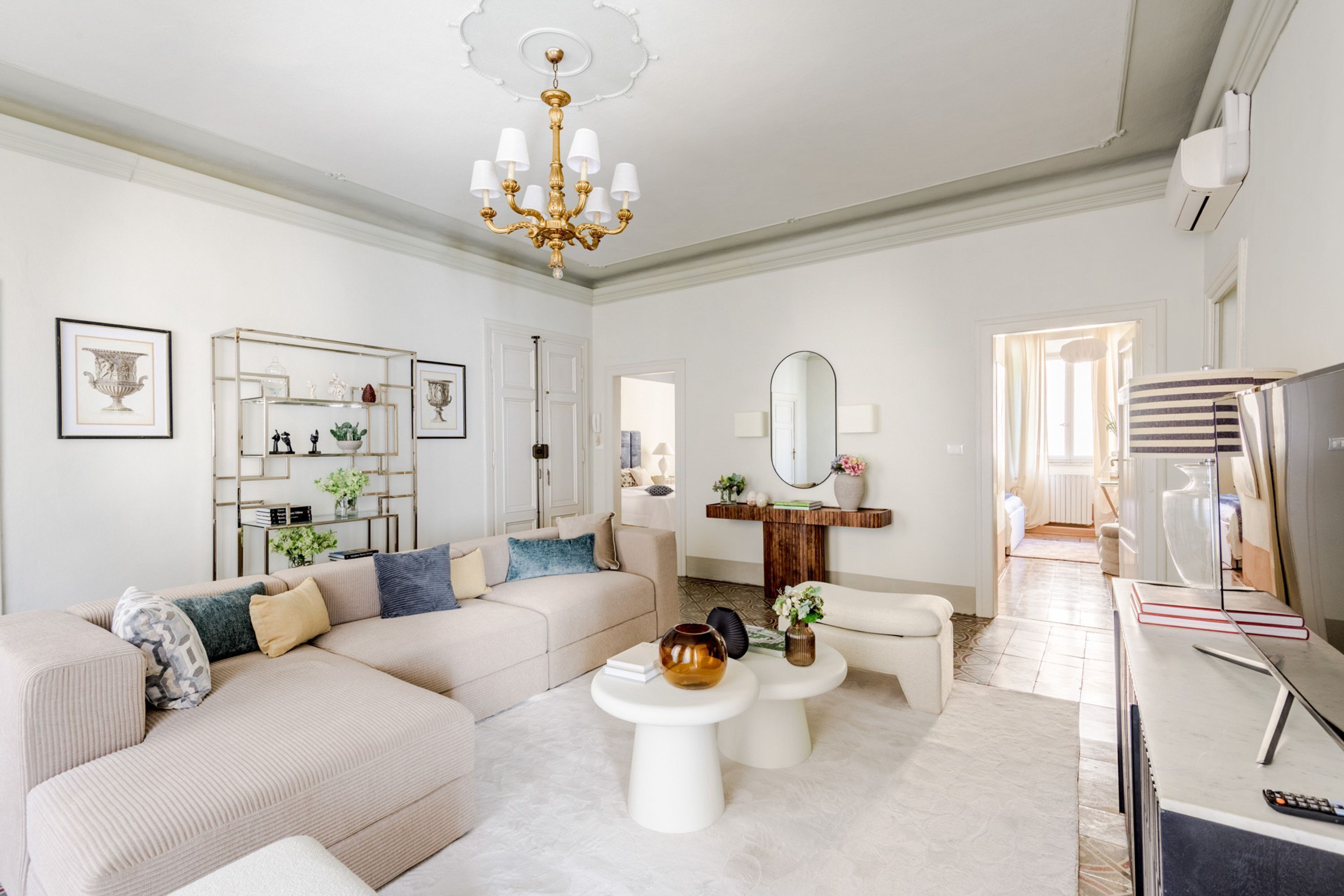 A modern living room with a sectional sofa, a coffee table, a TV, and a chandelier.