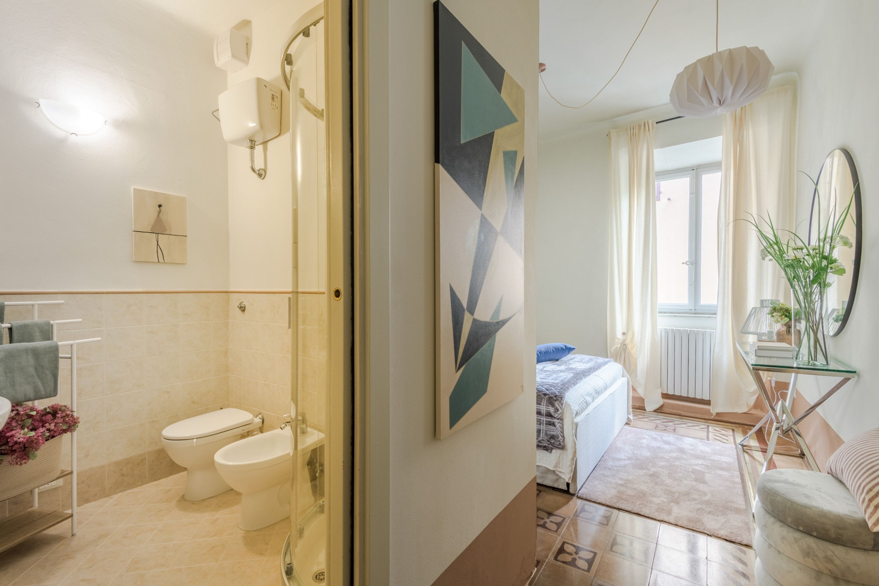 A bathroom with a toilet, bidet, and glass shower enclosure.