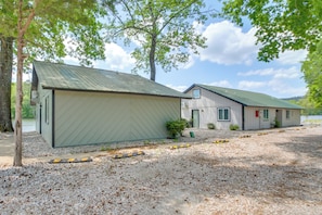 A building with a metal roof, a gravel driveway, and a small bush in front. - Waterfront Couples Retreat in Hot Springs! (Hot Springs)