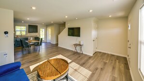 Un vaste espace de vie doté d’un plancher en bois, d’une table à manger et d’une cuisine à l’arrière-plan.