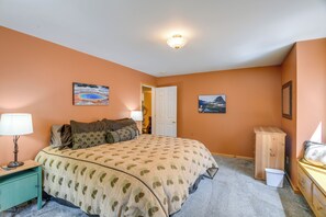A bedroom with a bed, a nightstand, a lamp, a dresser, and two wall-mounted pictures. - Extended-Stay 'Geyser Home' Near Yellowstone NP (West Yellowstone)