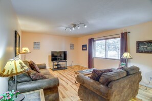 A living room with a television, two sofas, a coffee table, and a window with curtains. - Extended-Stay 'Geyser Home' Near Yellowstone NP (West Yellowstone)