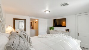 Et hotelværelse med en stor seng, et fjernsyn, en kommode og et spejl.
