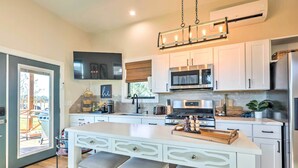 A modern kitchen with white cabinetry, stainless steel appliances, and a central island with bar stools. - 3 Cabins on Lake Conroe: Fish, Swim & Explore! (Willis)