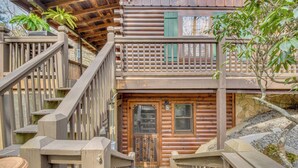 Una cabaña de madera con escaleras de madera, un felpudo y un muro de piedra.