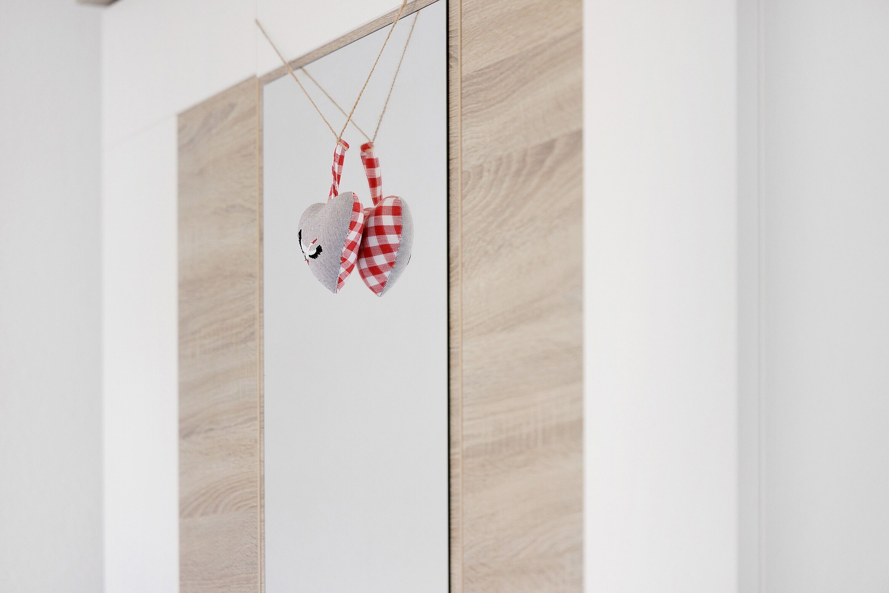 Eine Holzwand mit einem hängenden herzförmigen Schmuckstück.