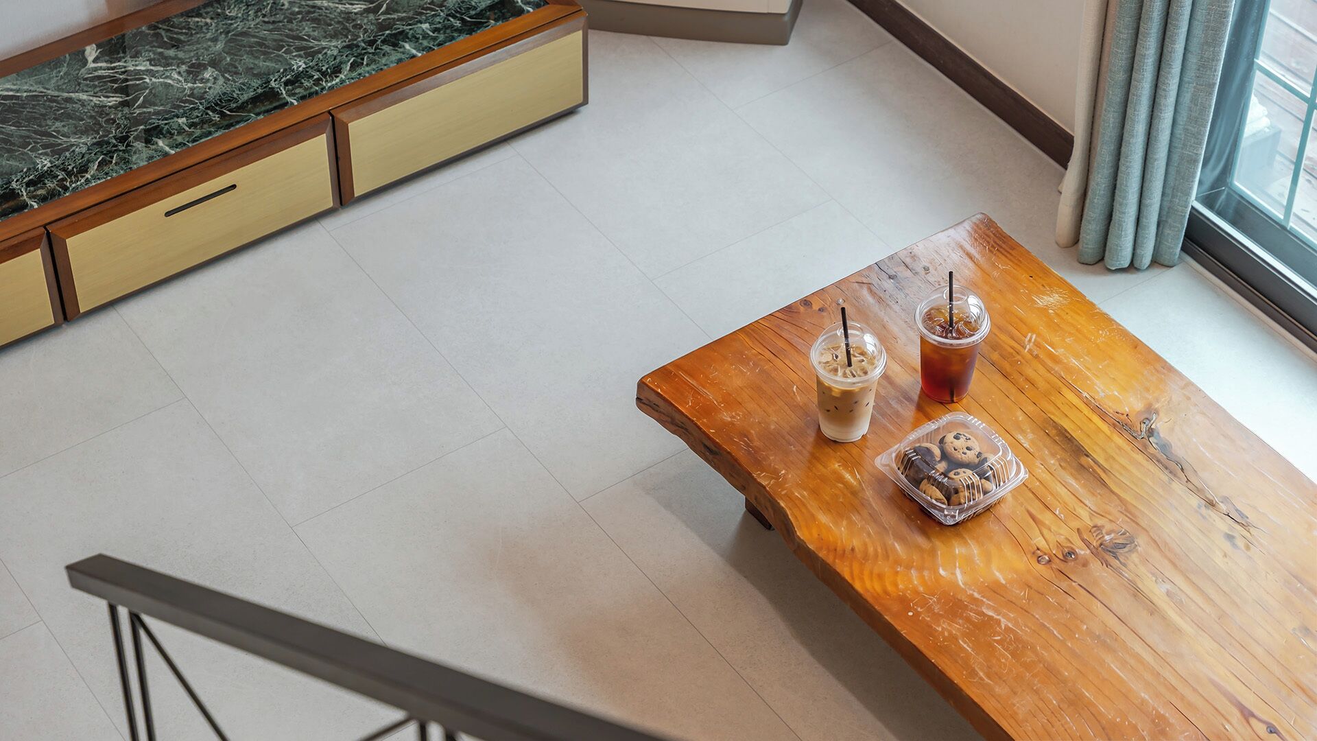 Une table en bois avec des boissons et des biscuits, un comptoir en marbre et un escalier.